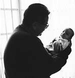 Social worker holding an infant, silhoueted by a window
