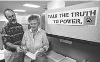 Union steward Tim Ferrell and Kathleen Shormann, in office infront of a sigh that says-Talk the Truth to Power.