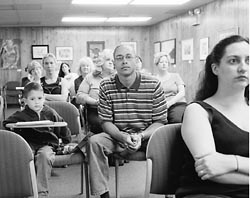 Audience members looking attentive at a town hall meeting.