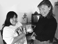 Wren Bardley and Maria. Maria is holding up photos of her family.