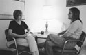 Therapist Peggy listening to Shara, they are sitting around a table with a table lamp